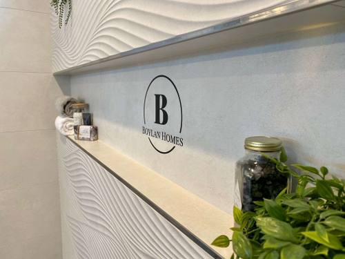 Stylish interior display featuring a textured wall, a logo for "Boylan Homes," and decorative elements including plants and towels, reflecting quality craftsmanship in home design.