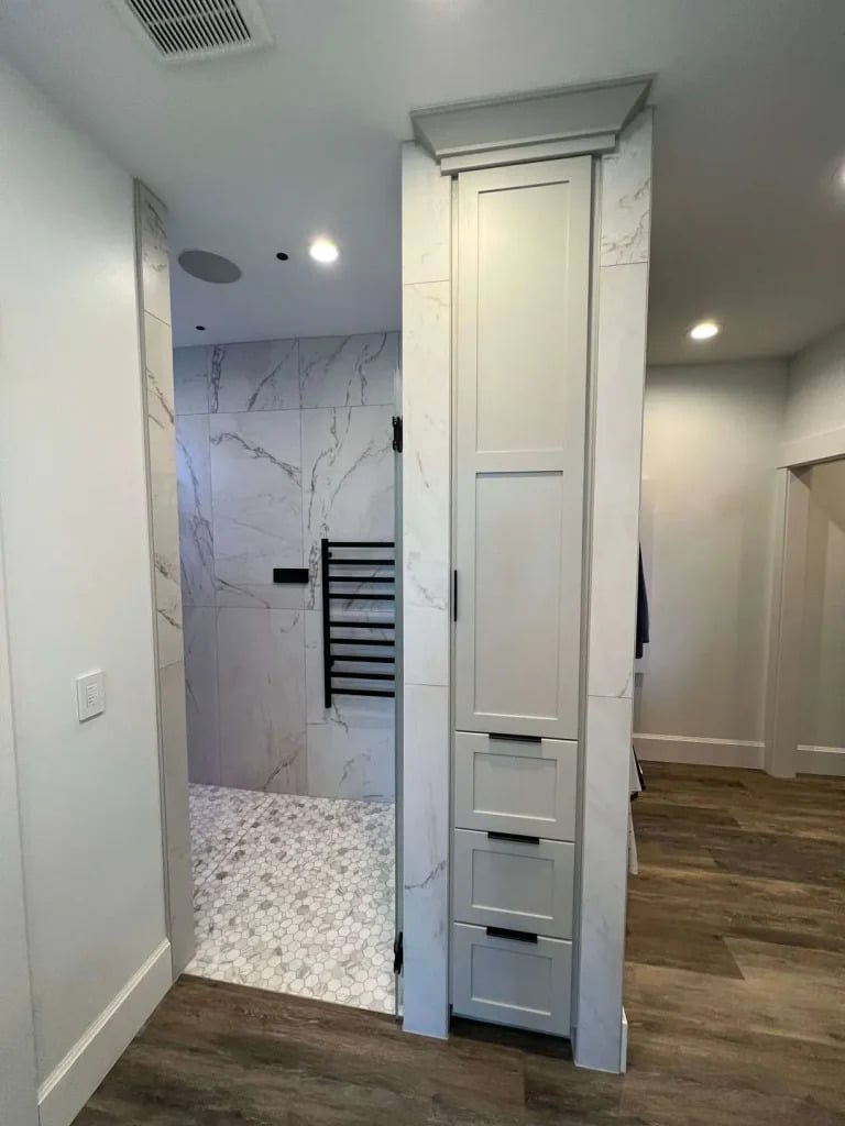 Modern bathroom interior featuring a marble shower wall, hexagonal tile flooring, and a sleek storage cabinet, illustrating NW Tile & Flooring's remodeling expertise in Dallas.