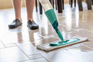 Person using a mop to clean newly installed tile flooring, showcasing the importance of maintaining cleanliness post-installation.