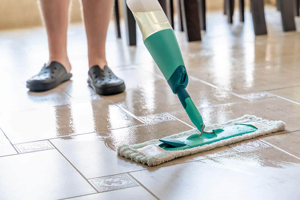 Person using a steam mop on newly installed ceramic tiles, demonstrating effective cleaning techniques for tile maintenance.