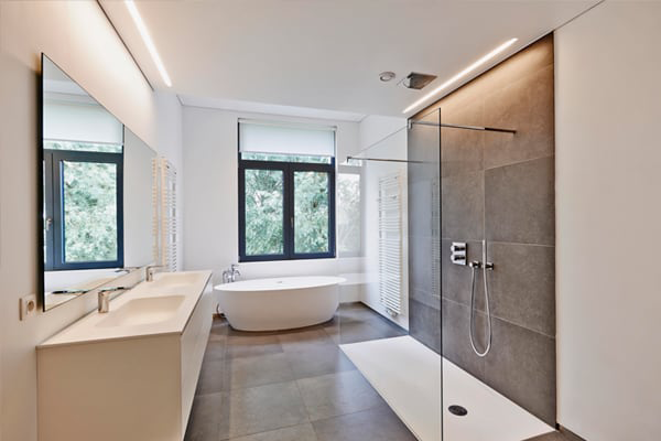 Modern bathroom design featuring sleek tile flooring, a glass shower enclosure, a freestanding bathtub, and large windows for natural light, showcasing expert tile installation.
