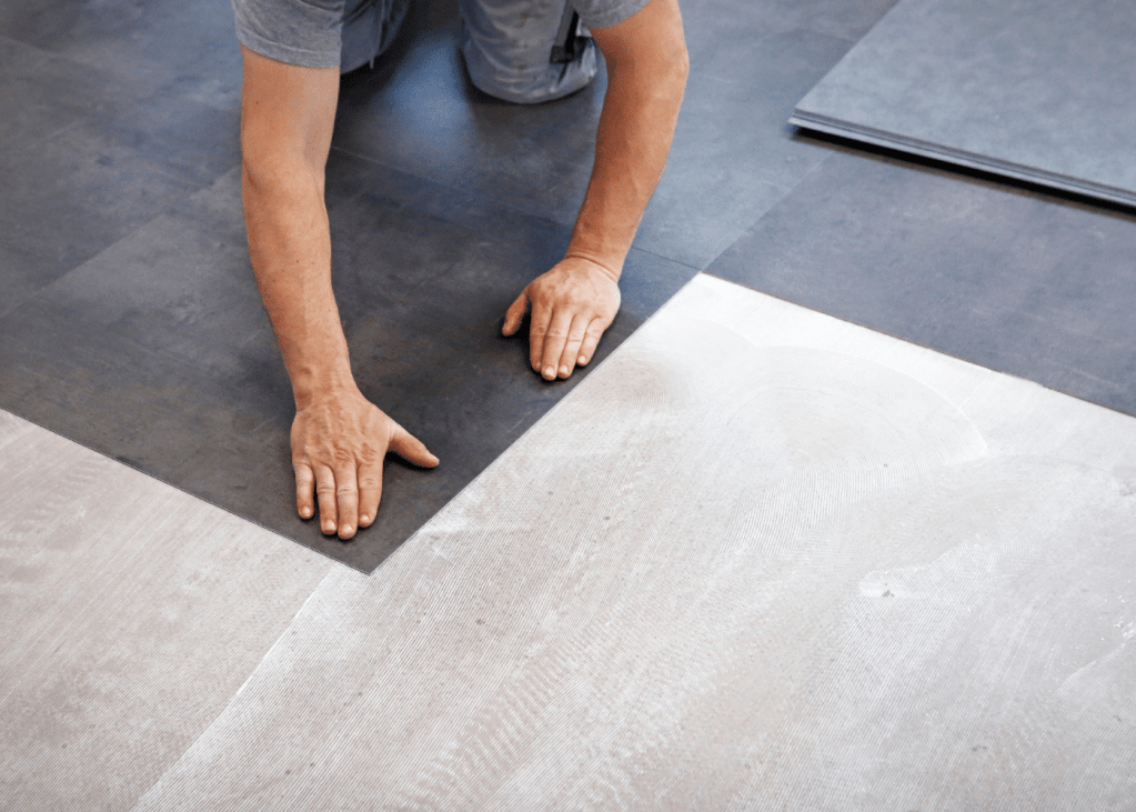 Man installing vinyl flooring, showcasing a mix of dark and light planks, emphasizing durability and style for home and commercial spaces in Keizer, Oregon.