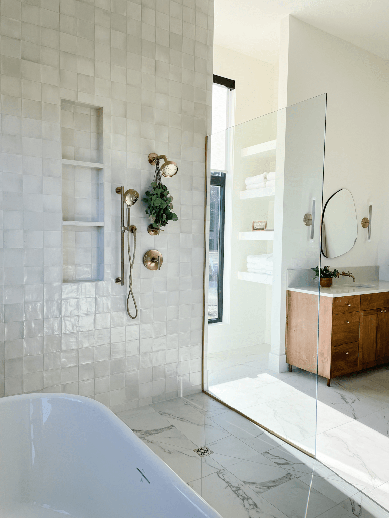 Bathroom remodel with white tile shower, marble floor, and brass fixtures