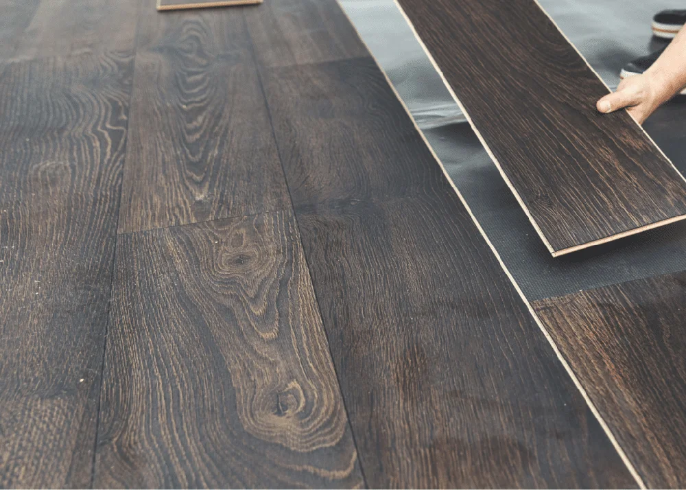 Installation process of laminate flooring, showcasing dark wood-look planks being placed on a surface, emphasizing durability and aesthetic appeal for residential or commercial spaces in Salem, Oregon.