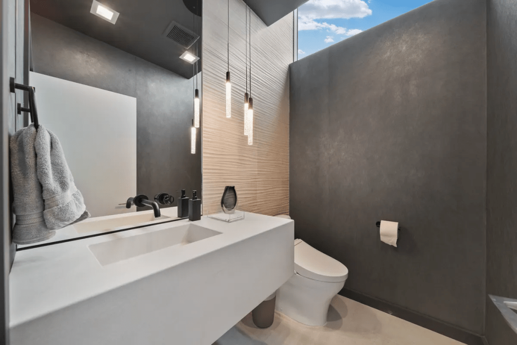Modern bathroom featuring a sleek quartz countertop sink, textured wall tiles, and minimalist design elements, emphasizing luxury and coastal aesthetics.