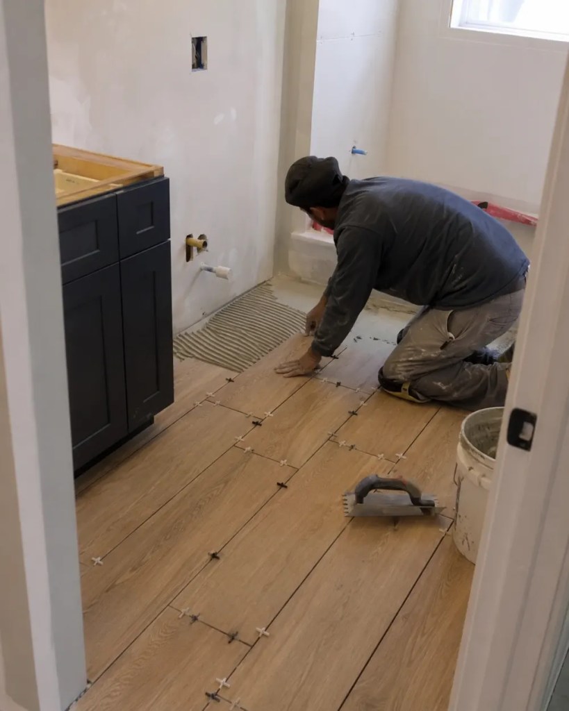 Bathroom remodel team measuring tile lines inside an Albany - OR home before shower wall installation